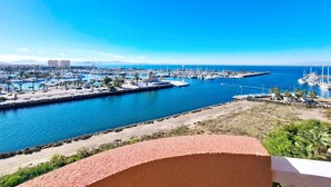 A marina with boats, a clear blue sky, and a distant mountain range.