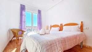 A bedroom with a bed, a chair, and a window with curtains.
