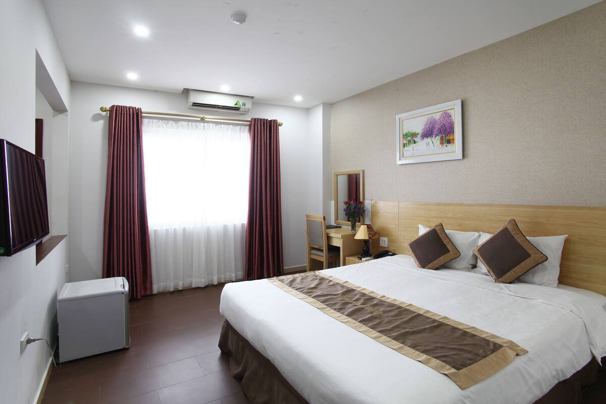 Ein Hotelzimmer mit Bett, Nachttisch, Lampe und Fernseher.