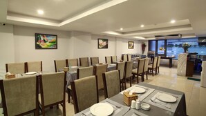 A dining area with tables set for four, chairs, and artwork on the walls. - Blue Pearl Hotel (Hanoi)