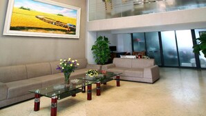 A modern living room with a glass coffee table, a sofa, and a large painting on the wall. - Blue Pearl Hotel (Hanoi)