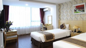 A hotel room with a bed, bedside table, lamp, and a desk with a chair and flowers. - Blue Pearl Hotel (Hanoi)