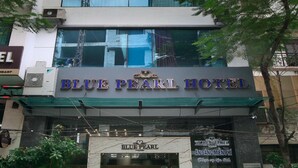 The exterior of the Blue Pearl Hotel with a clear entrance, air conditioning units, and surrounding greenery. - Blue Pearl Hotel (Hanoi)