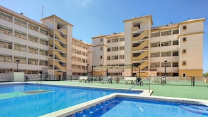 A swimming pool surrounded by a multi-story building with balconies.