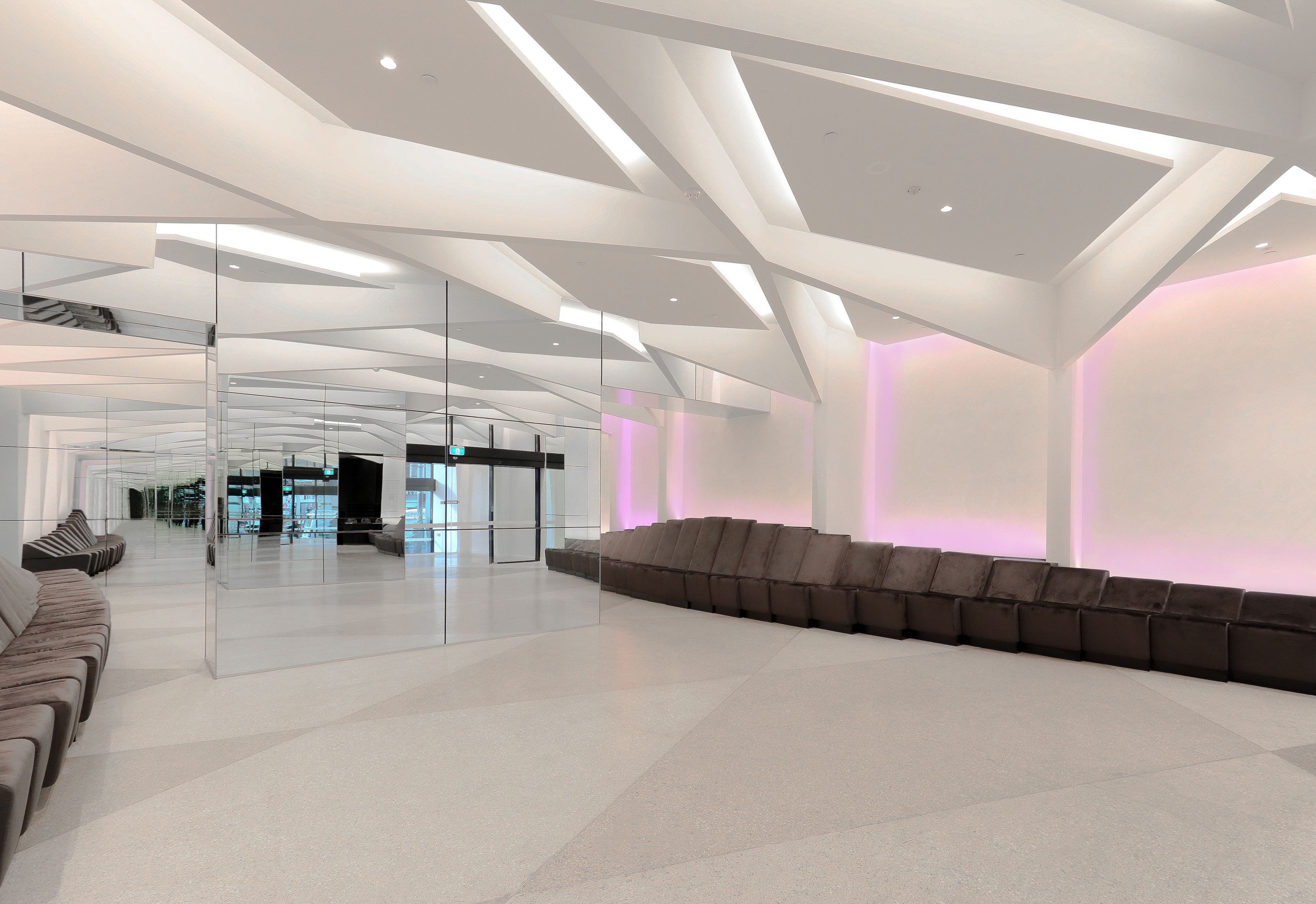 Een ruime lobby met een modern ontwerp, met een lange zithoek en een glazen scheidingswand.