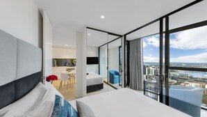 A modern hotel room with a large bed, a view of the city, and a separate dining area.