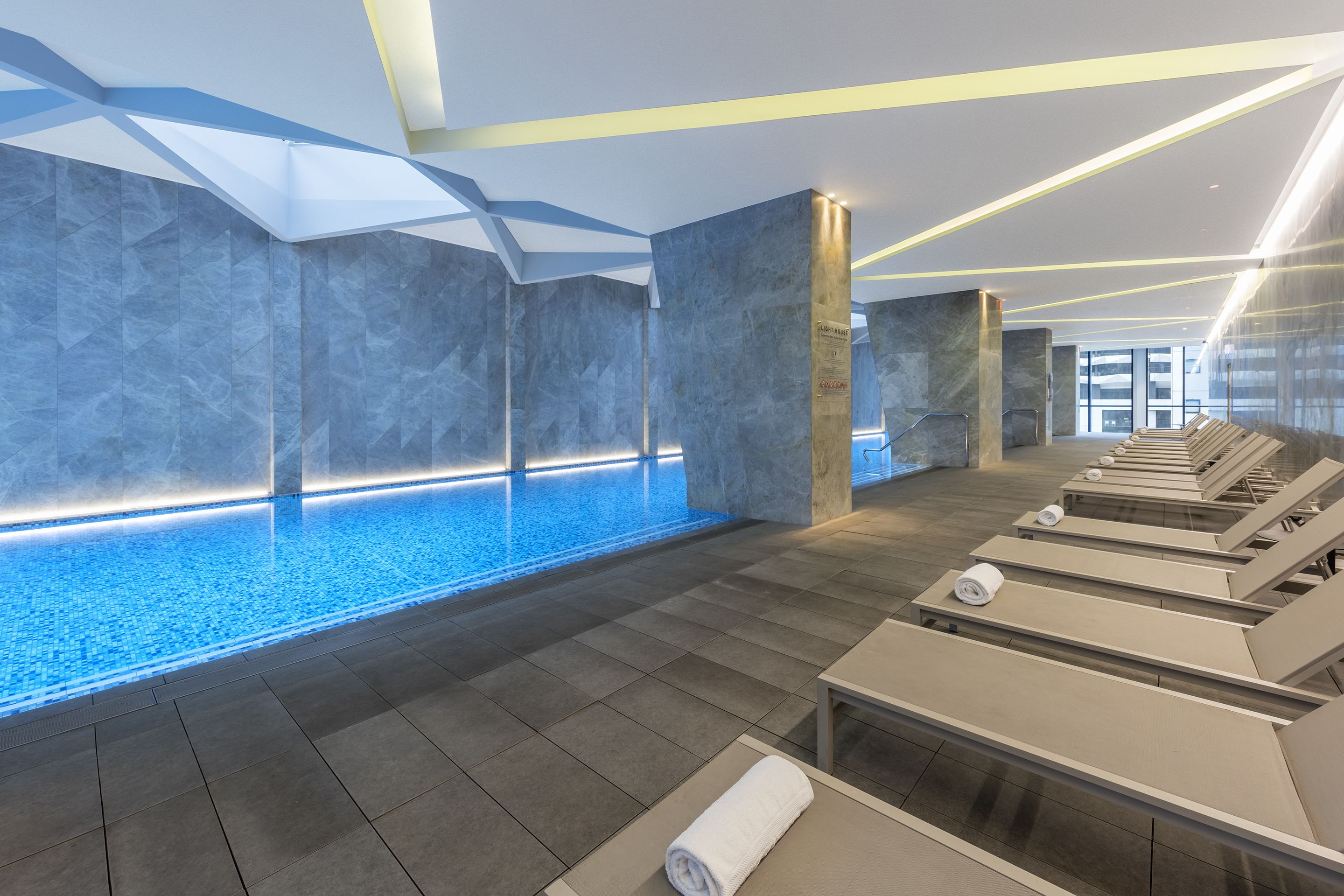 A modern spa area with a pool, lounge chairs, and a tiled floor.