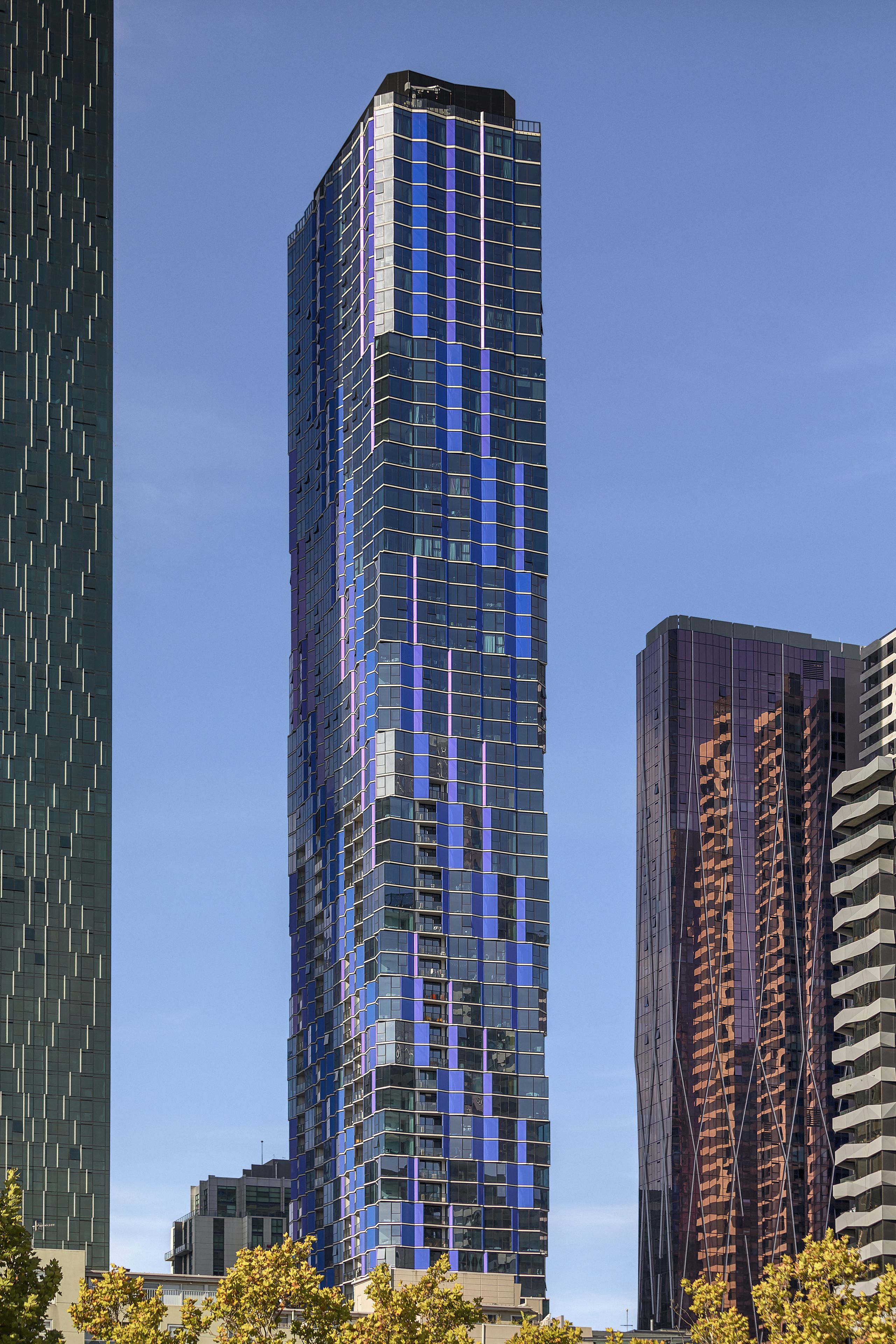 A modern high-rise building with a distinctive blue and purple facade, surrounded by other tall buildings.