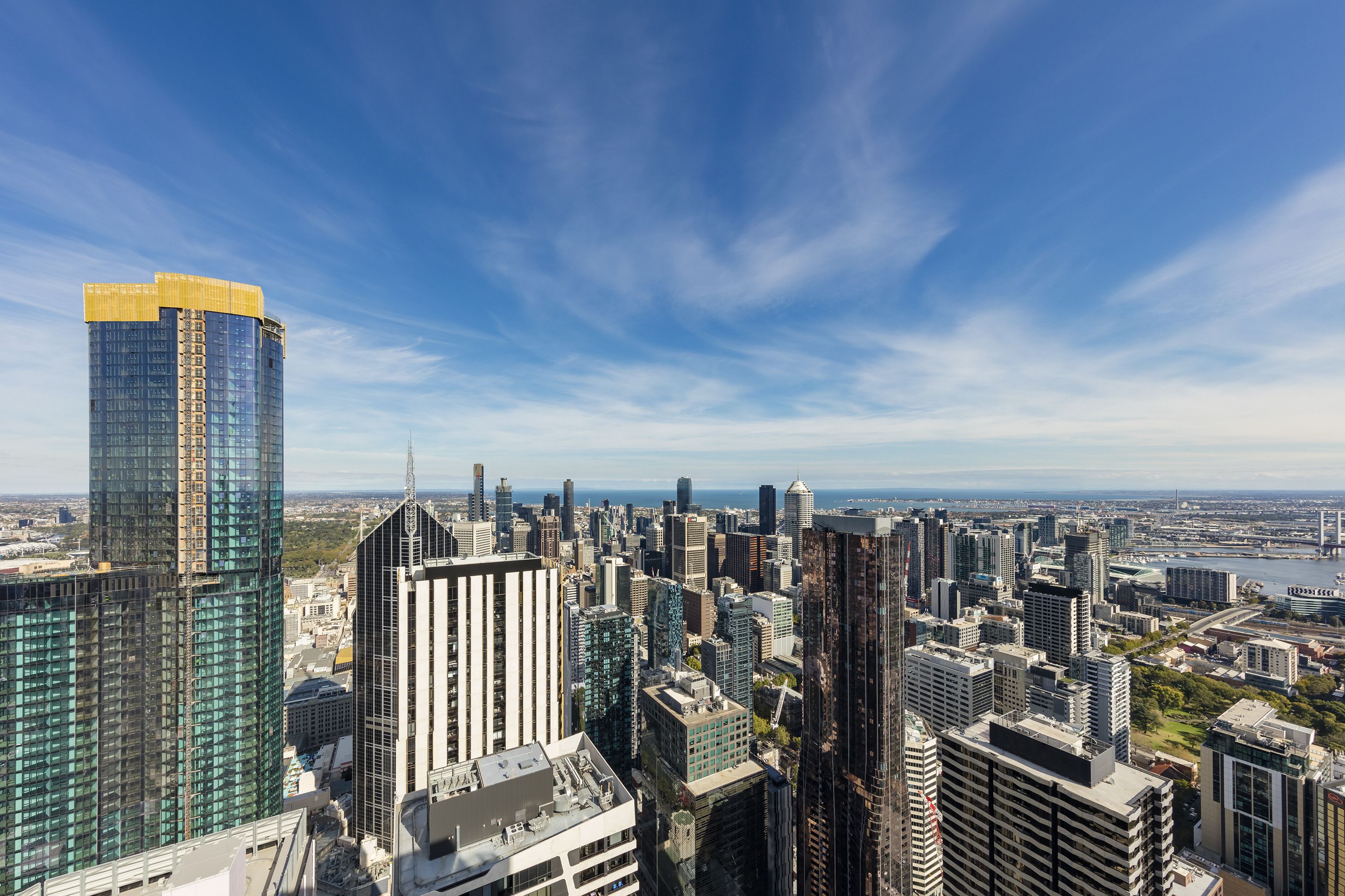 Paisagem urbana com arranha-céus e arquitetura moderna, incluindo um edifício de destaque com topo amarelo e fachada de vidro.
