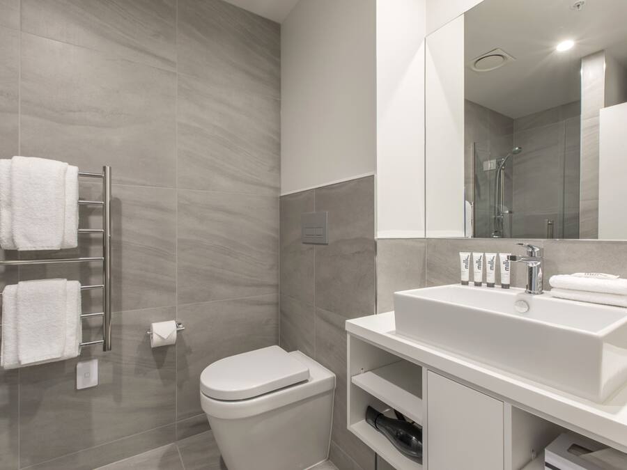 A modern bathroom with a white sink, mirror, and towel rack.