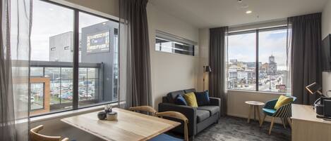 Et moderne hotelværelse med spiseplads, en sofa og udsigt over byen.