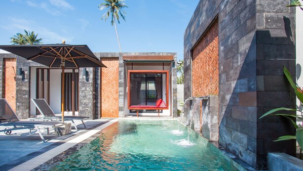 Un área de piscina moderna con sillones de descanso, un banco y una cascada.
