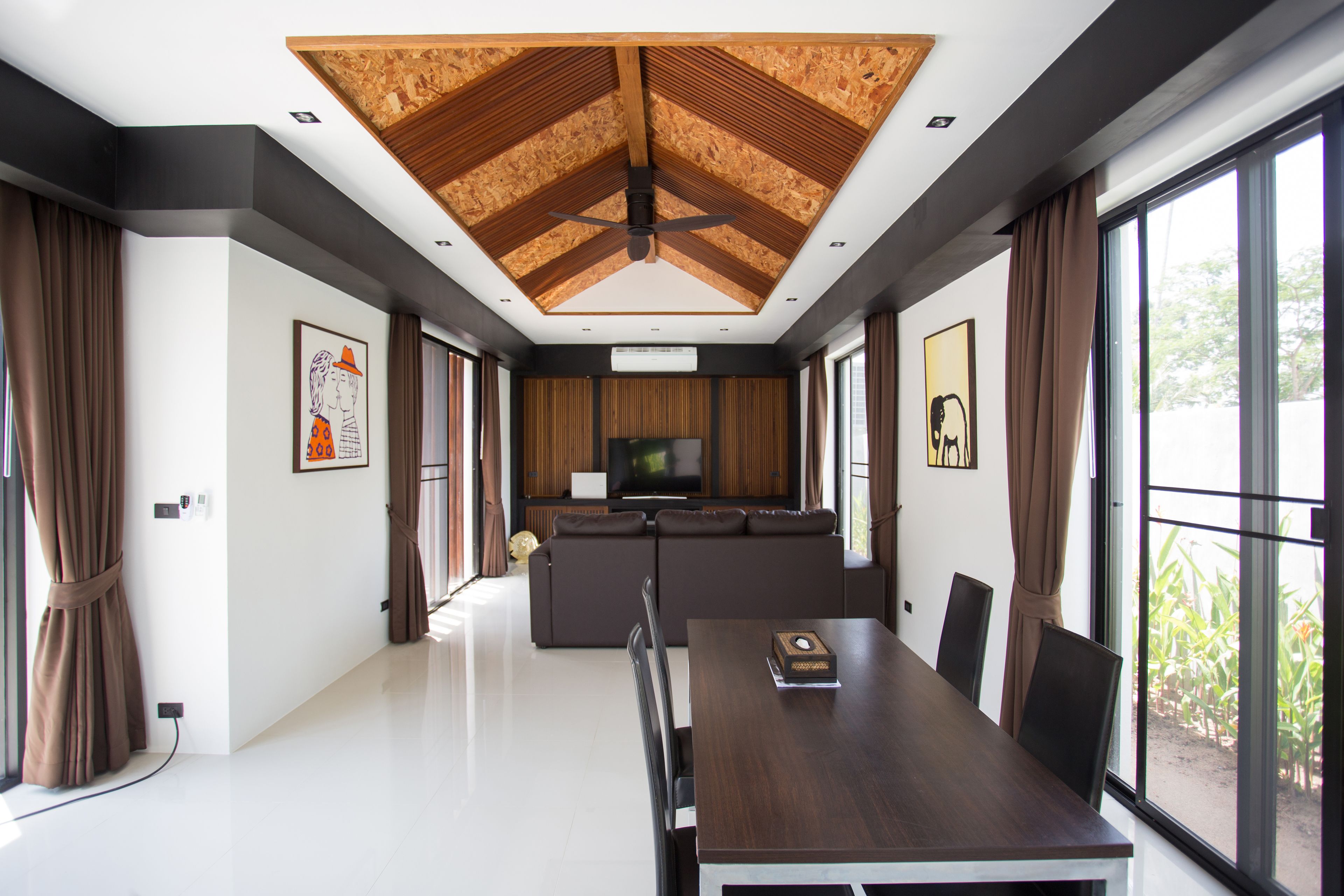 A modern living room with a large TV, a dining table, and a sofa.