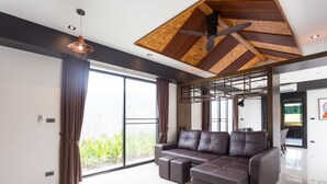 Una sala de estar moderna con un sofá modular, ventanas amplias y un ventilador de techo.