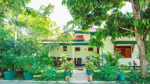 A traditional building with a tiled roof, surrounded by lush greenery and potted plants. - Nehansa Resort and Safari (Thissamaharama)