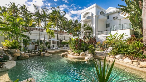 Ett semesterparadis med en swimmingpool omgiven av palmer och solstolar.