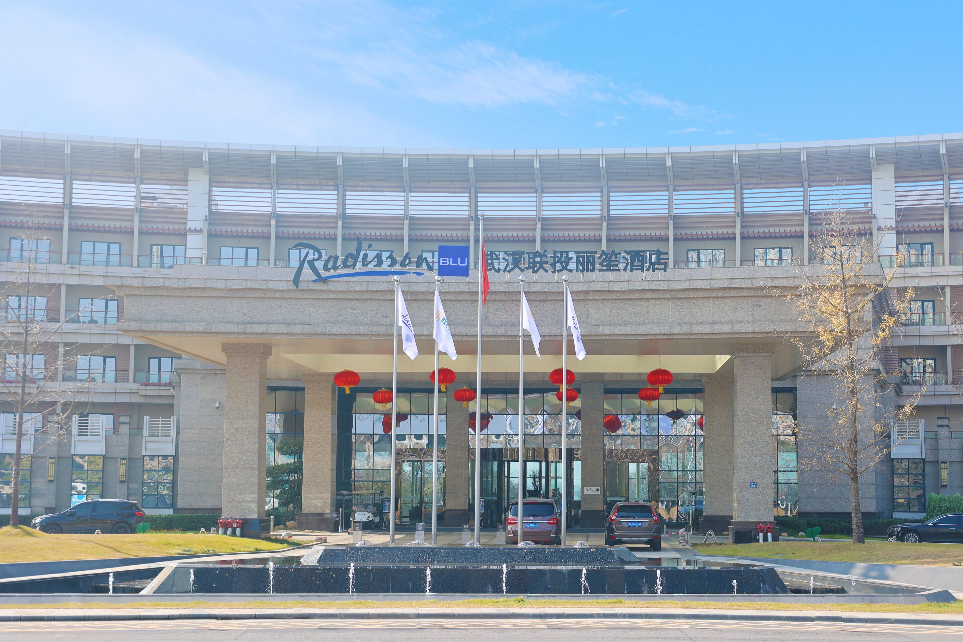 A modern building with a large entrance, multiple flags, and red lanterns.