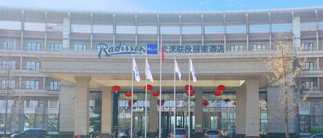 A modern building with a large entrance, multiple flags, and red lanterns.
