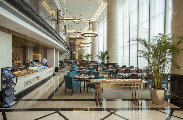 A spacious hotel lobby with a reception desk, multiple dining tables, and chairs, large windows, and a modern chandelier. - Radisson Blu Hotel Wuhan ETD Zone (Wuhan)