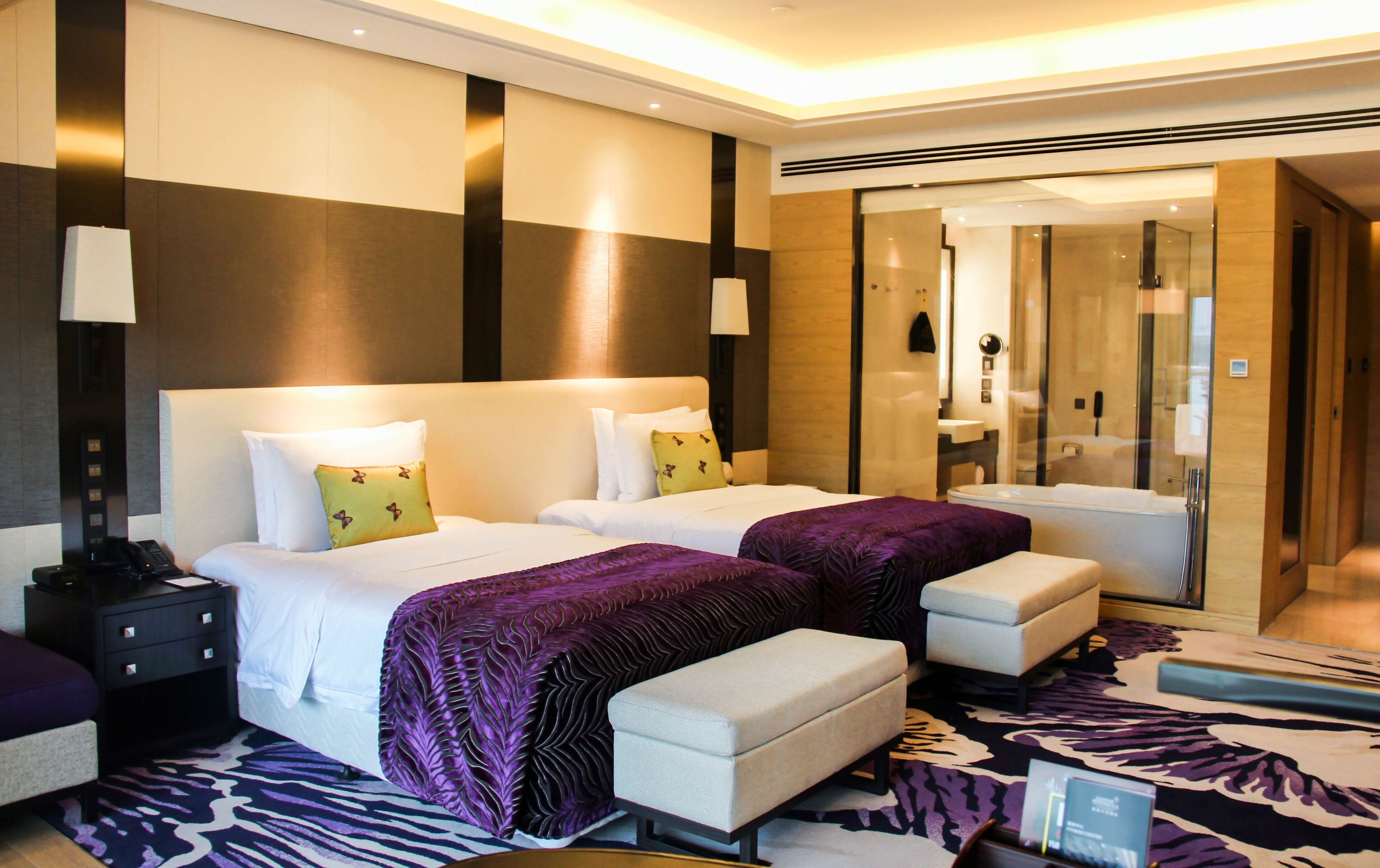 Habitación de hotel con dos camas, zona de estar, ducha y un espejo grande.