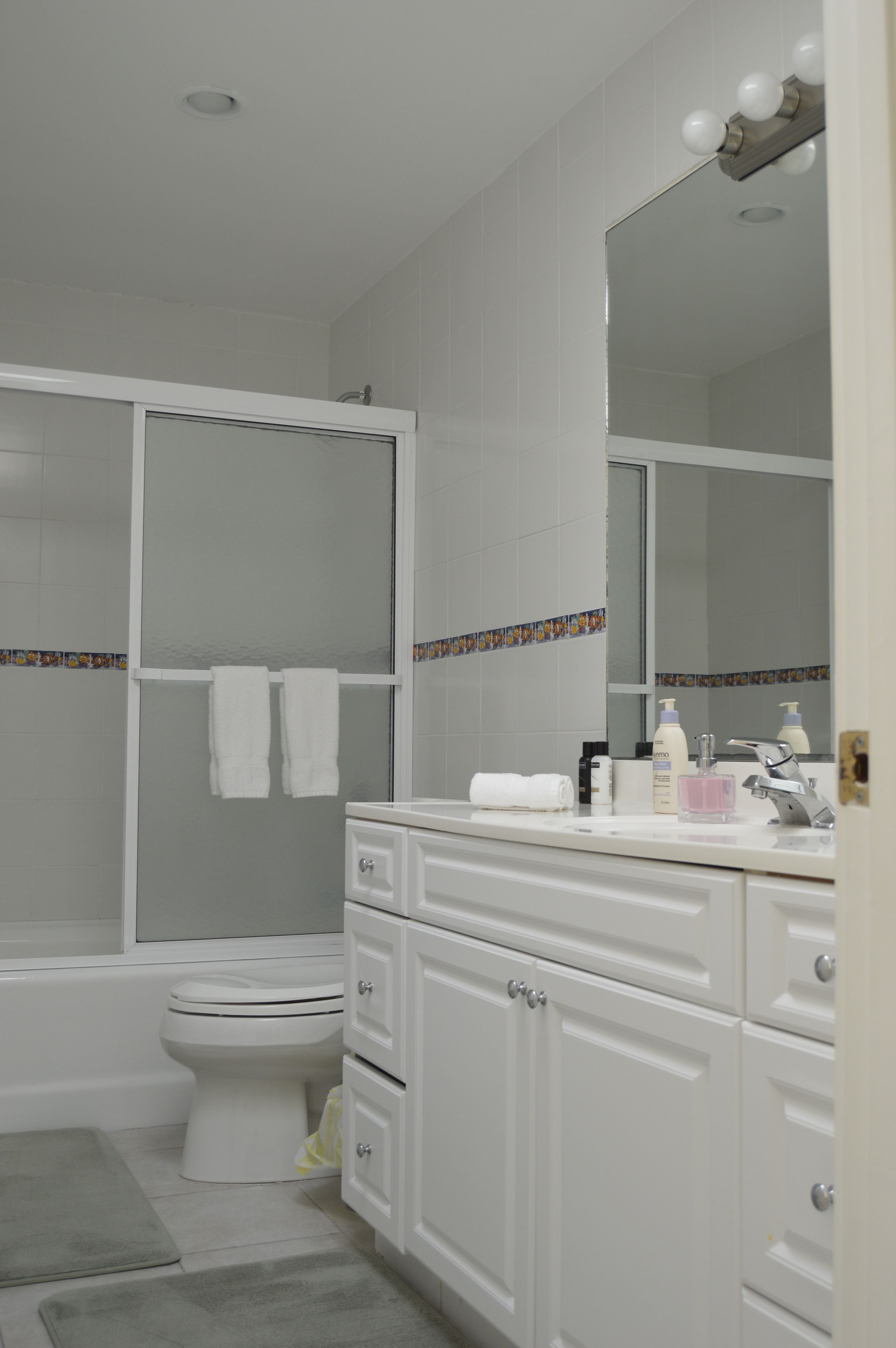 Une salle de bain équipée d’une douche, de toilettes et d’un meuble-lavabo avec des tiroirs et un miroir.