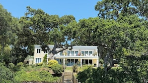 A waterfront property with a wooden dock leading to a two-story house.