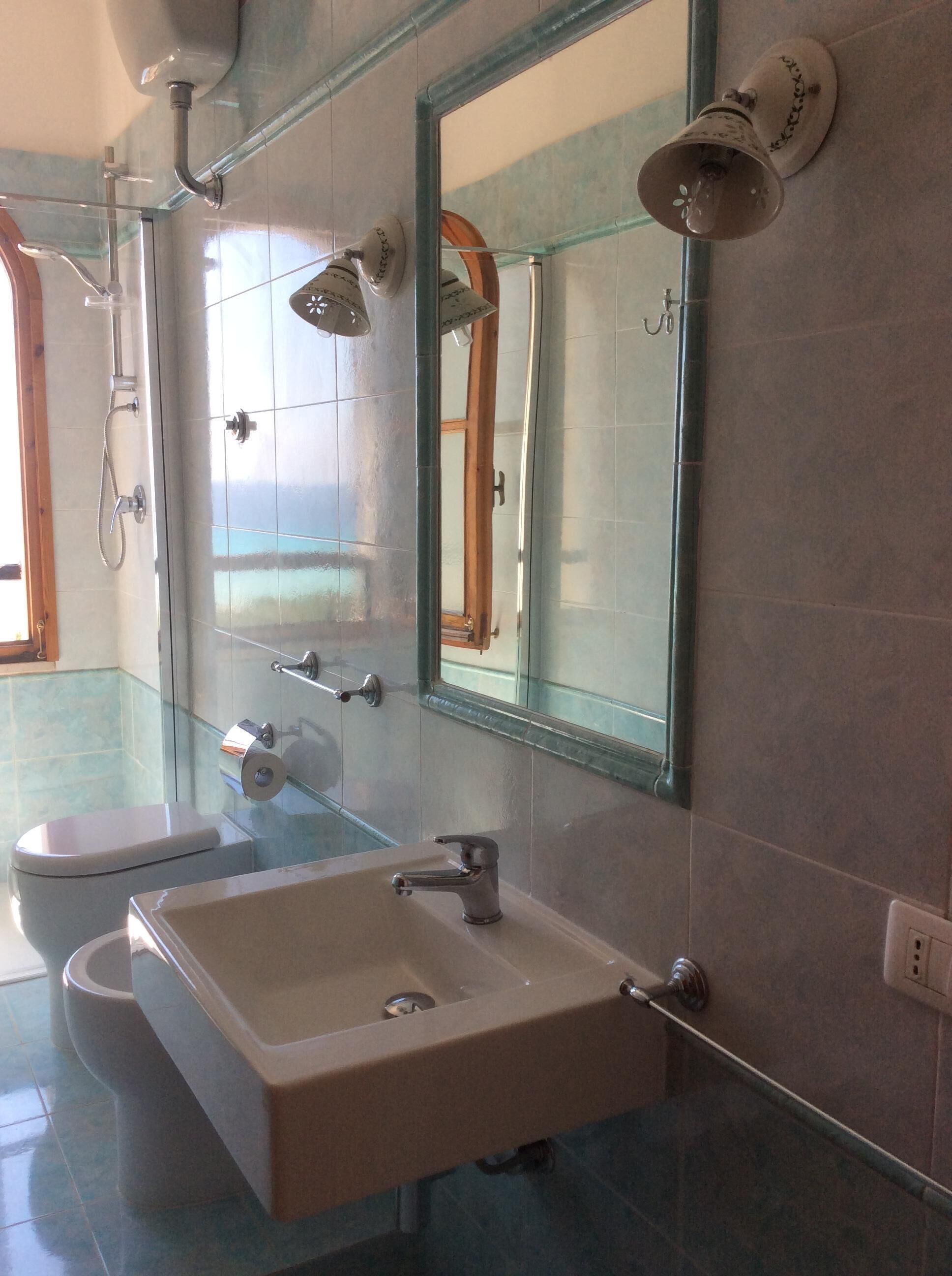 Ein Badezimmer mit Toilette, Waschbecken, Dusche und Spiegel.