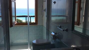 Ein Badezimmer mit einer Glastür, die auf einen Balkon mit Meerblick führt.