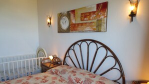 A bedroom with a bed, nightstand, and wall-mounted lamp. - Large panoramic apartment, beautiful sea view. (Costa Rei)
