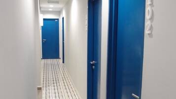 A corridor with blue doors, each marked with a number. The floor has a striped pattern.