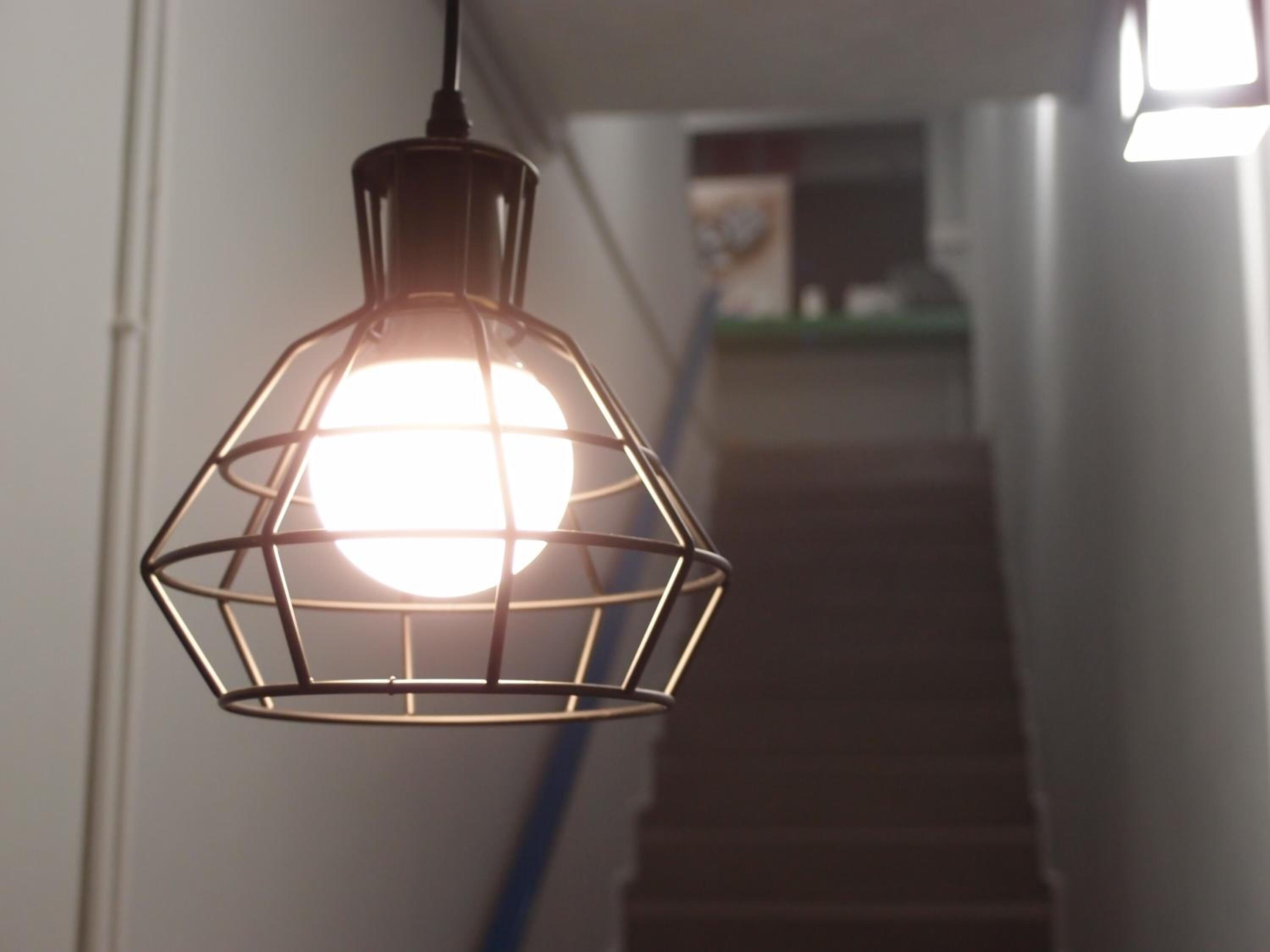 Un luminaire suspendu, de type suspension, avec une ampoule sphérique et un cadre métallique aux formes géométriques.