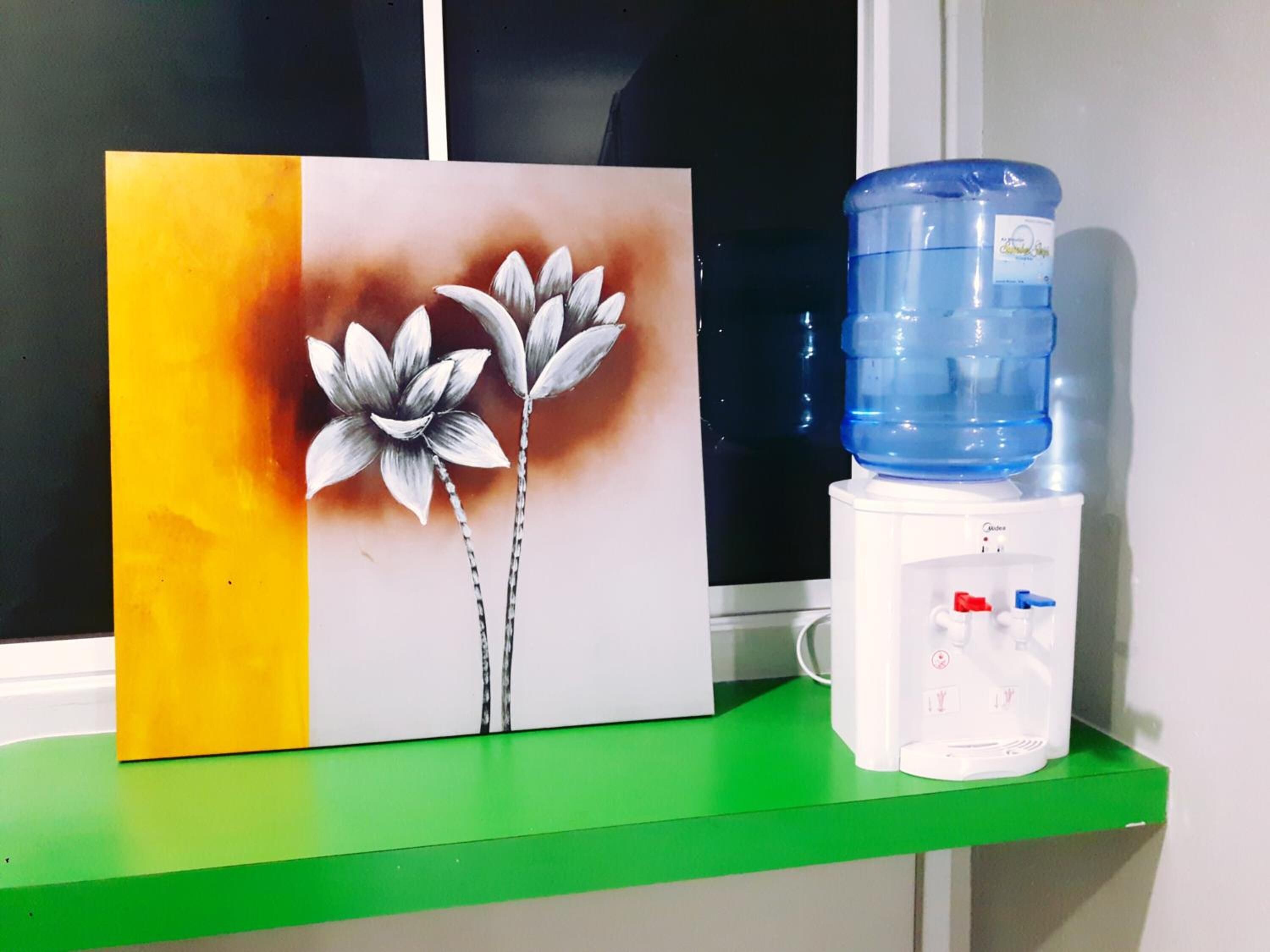 A water dispenser and a painting on a green shelf.