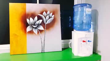 A water dispenser and a painting on a green shelf.