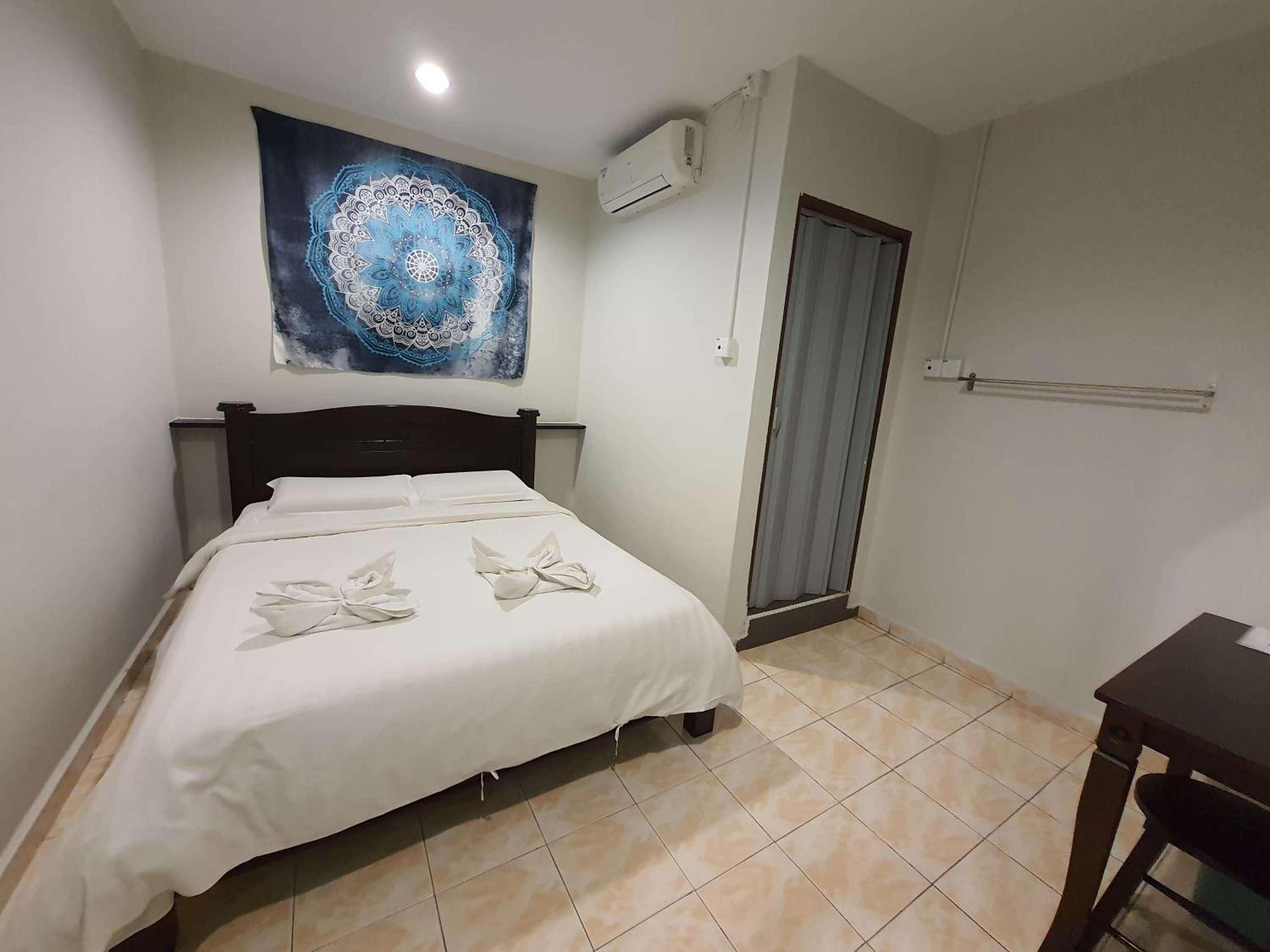 A bedroom with a bed, a wall-mounted air conditioner, a door, and a small table.