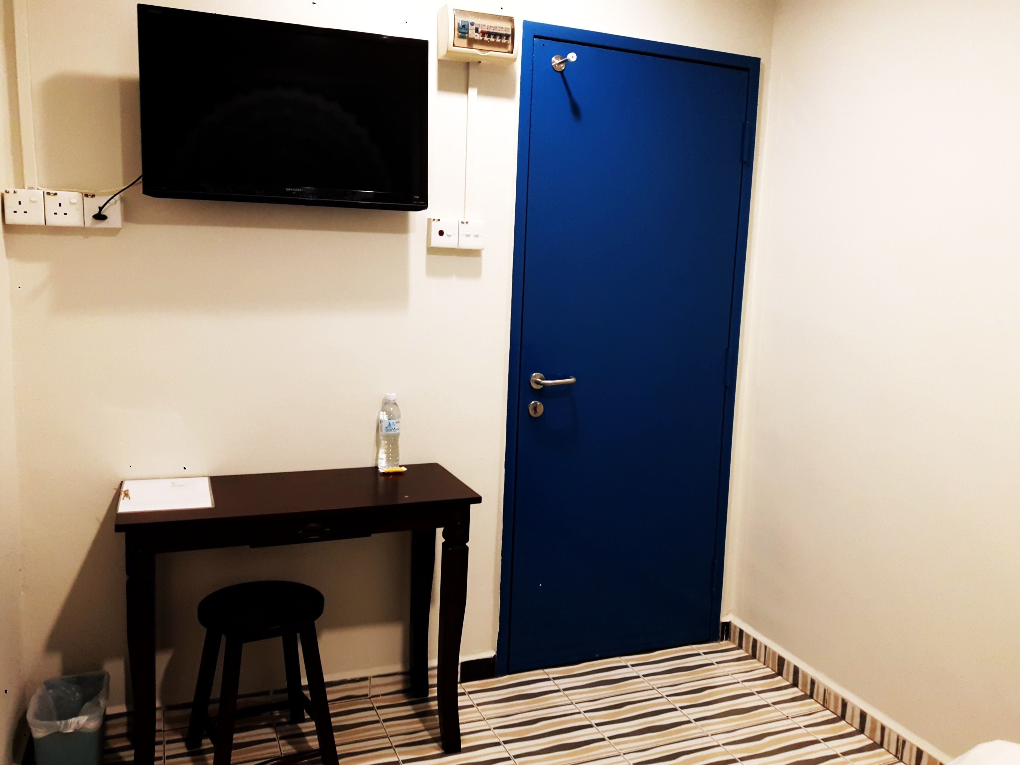 Une pièce avec un bureau, une chaise, un téléviseur et une porte bleue.