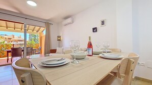A dining area with a table set for four, a bottle of wine, and a lamp.