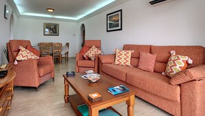 Een woonkamer met twee banken, een salontafel en een eethoek met stoelen en een tafel.
