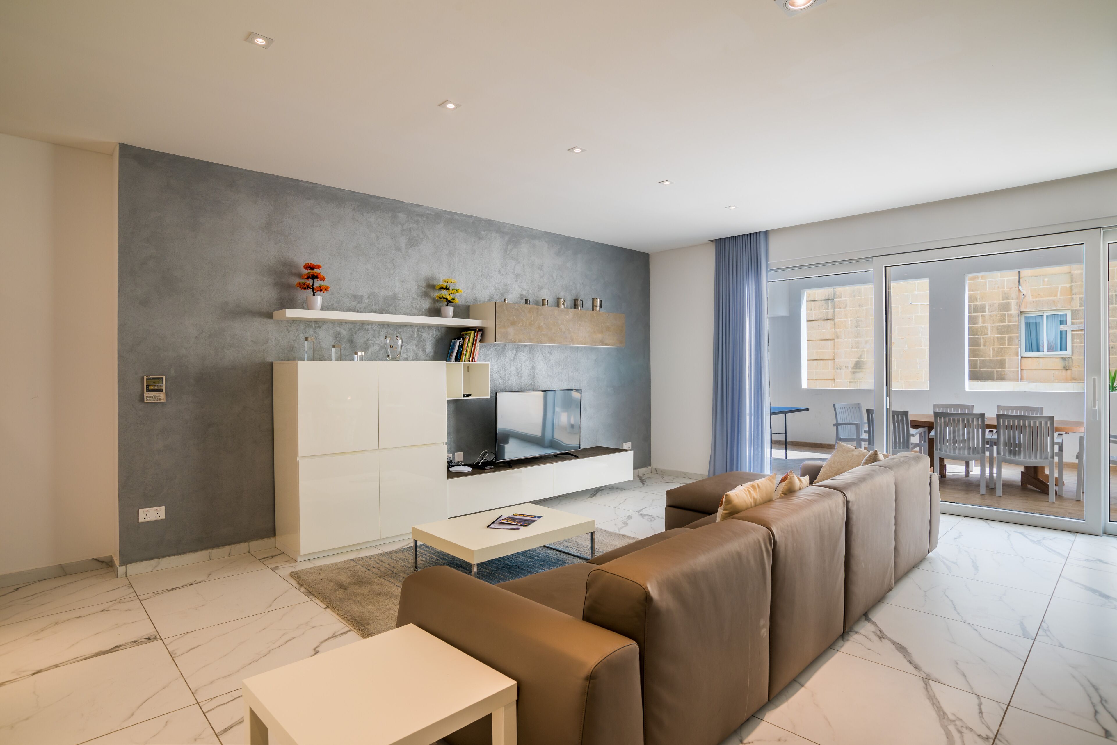 Un salon moderne avec un grand canapé, un téléviseur à écran plat et un coin repas comprenant des chaises et une table.