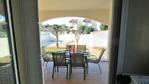 An open patio with a table and chairs, a tiled floor, and a view of a residential area with houses and trees. - Magnificent Villa with private pool on large plot unlimited free wifi (L'ESCALA)