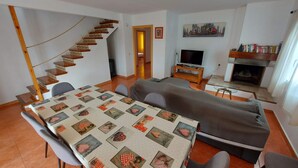 A living room with a dining table, sofa, TV, fireplace, and a spiral staircase. - Magnificent Villa with private pool on large plot unlimited free wifi (L'ESCALA)