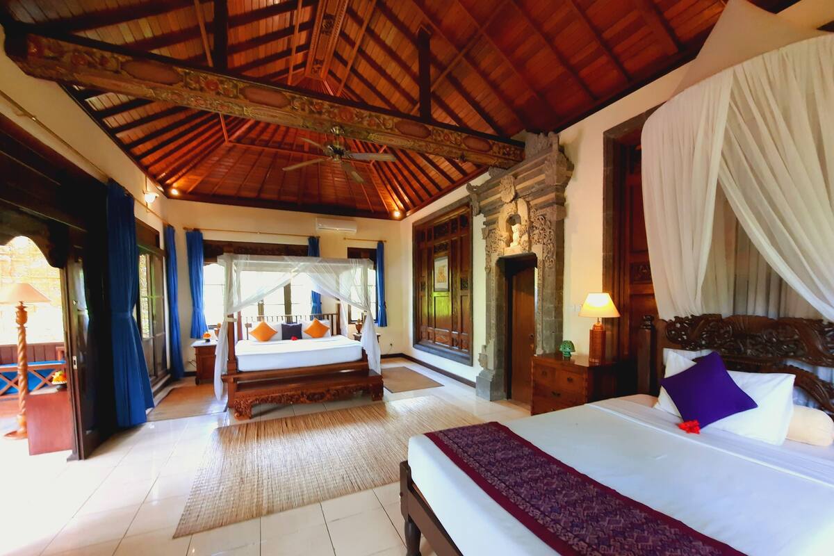 Ruime slaapkamer met een groot bed, een plafondventilator en uitzicht op de omgeving.