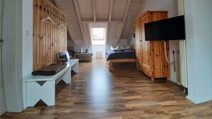 Ett mysigt sovrum på vinden med en träbänk, en säng, en tv och en trägarderob.