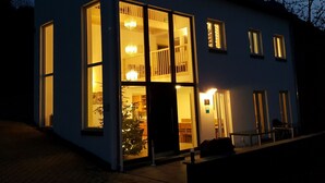 En modern byggnad med stora fönster, en trappa och ett julgran som syns inifrån.