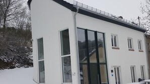 En modern byggnad med stora fönster och en ingång som är skyddad av ett tak.