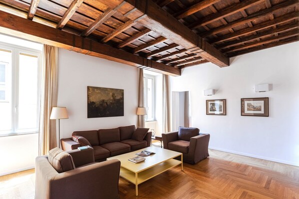 A living room with a wooden ceiling, a sofa set, a coffee table, and framed pictures on the wall.