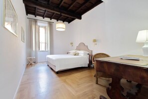 A room with a bed, a wooden desk, a chair, and a hanging light fixture.