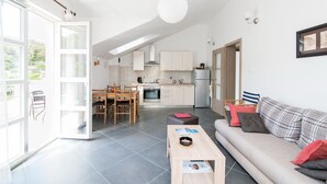 Een modern appartement met een eethoek, kitchenette en een woonkamer met een bank en salontafel.