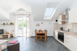 A modern kitchen with a dining area, featuring a skylight, a built-in oven, and a large window.