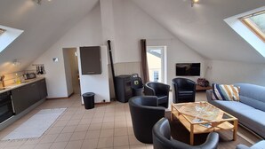 Ein modernes Loft mit Küche, Essbereich und Wohnzimmer. Es verfügt über ein großes Dachfenster, einen Kamin und einen Fernseher.