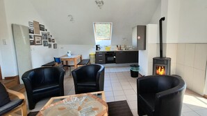 Ein Wohnzimmer mit Kamin, Essbereich und Küche mit Fenster.